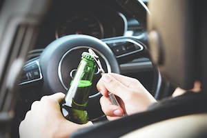 DUI Attorney in Los Angeles County View of a Person Sitting in a Car Opening a Bottle of Beer