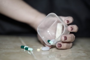 DUID Attorney in Los Angeles County Person’s Hand Holding a Container of Pills with the Pills Spilled Out on a Table