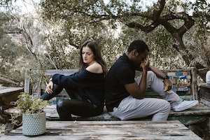 Los Angeles County Domestic Violence Defense Lawyer Distressed Couple Sitting Back to Back on a Bench Outdoors